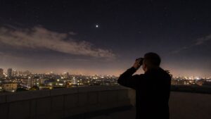 Night-sky scene illustrating urban observing as contrast management: target selection, local shielding, timing, altitude, and repeatable micro-sites