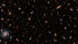 Illustrative deep galaxy field continuing beyond the frame, with tiny remote red galaxies and a small blue spiral near one corner.